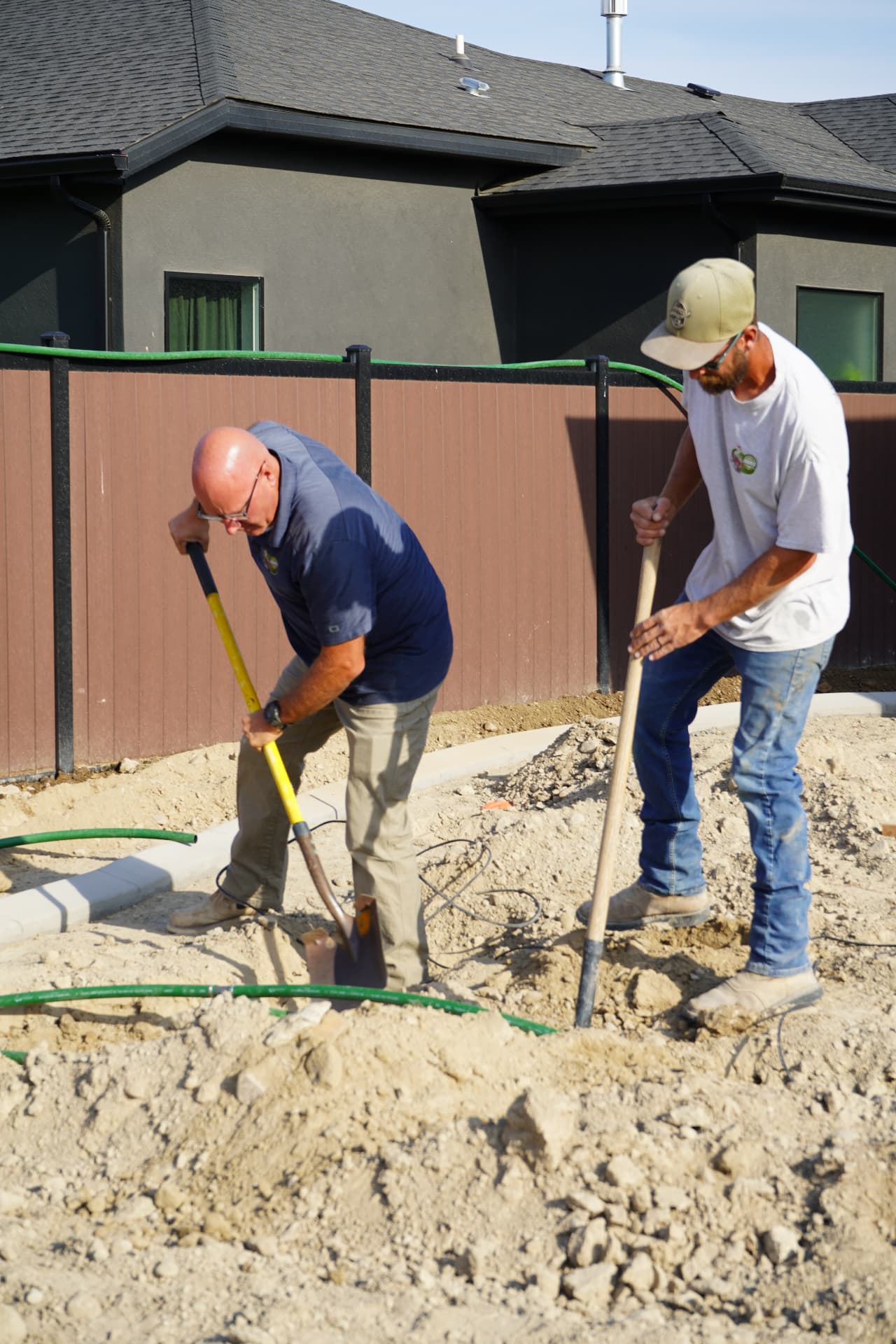 Two Hanks crew members digging for a new sprinkler system install