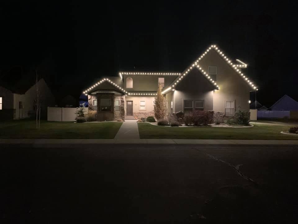 Single-story home with warm white LED Christmas lights outlining the roofline at night