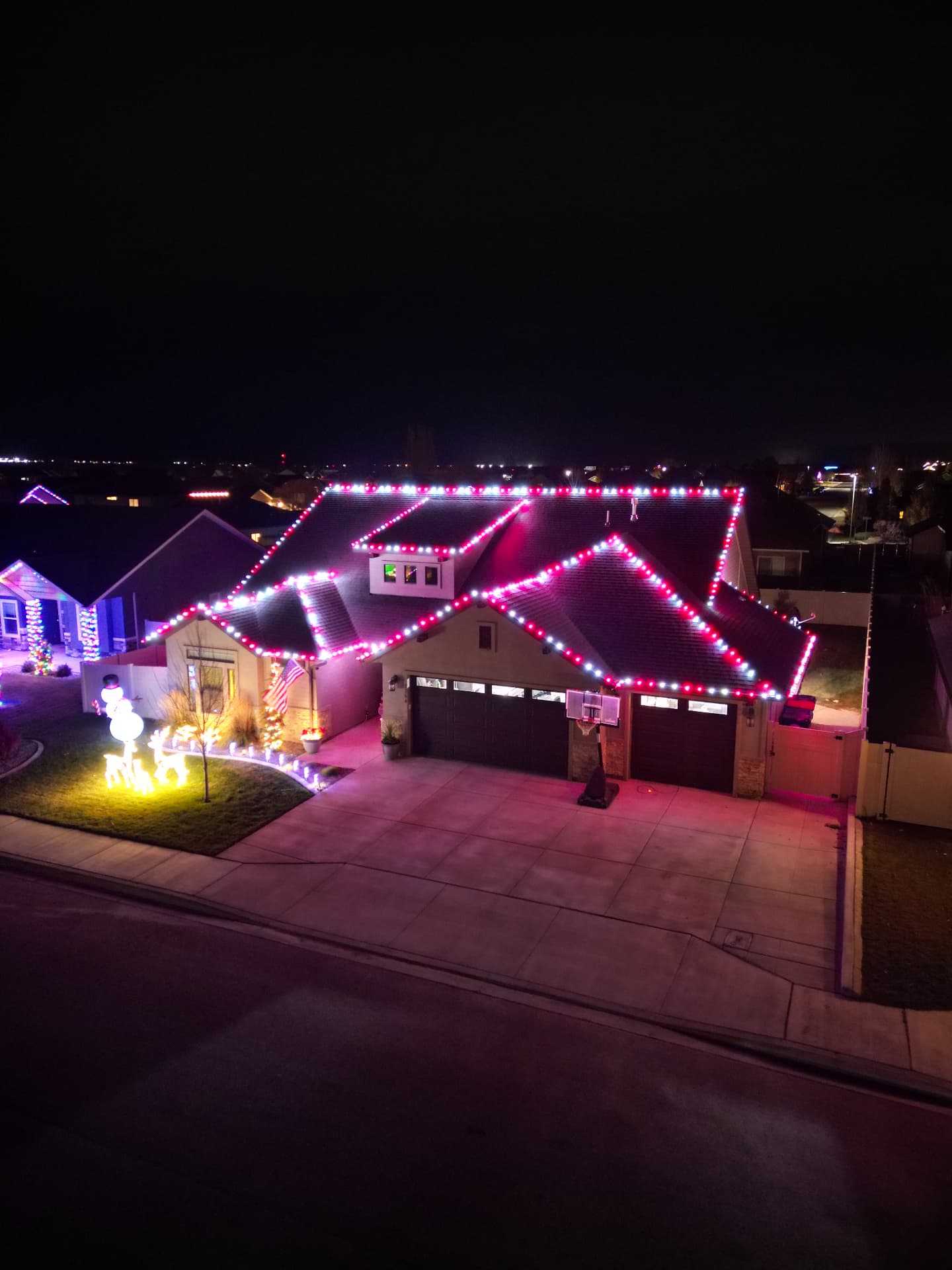 Two-story home with red and white Christmas lights and glowing yard figures
