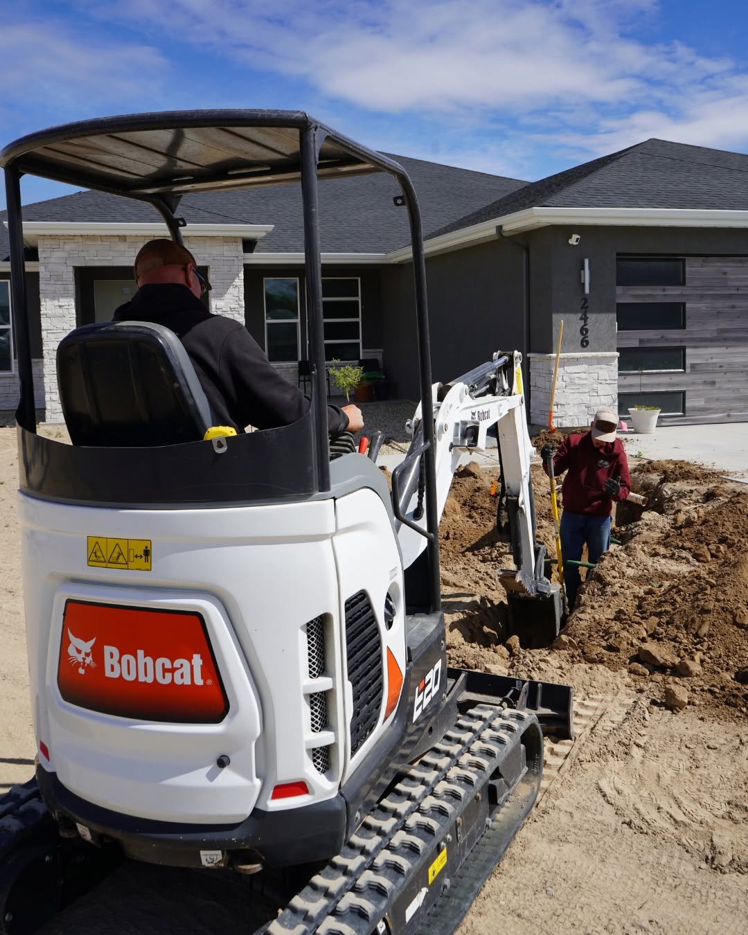 Bobcat E20 excavator digging for a sprinkler system install at a new home