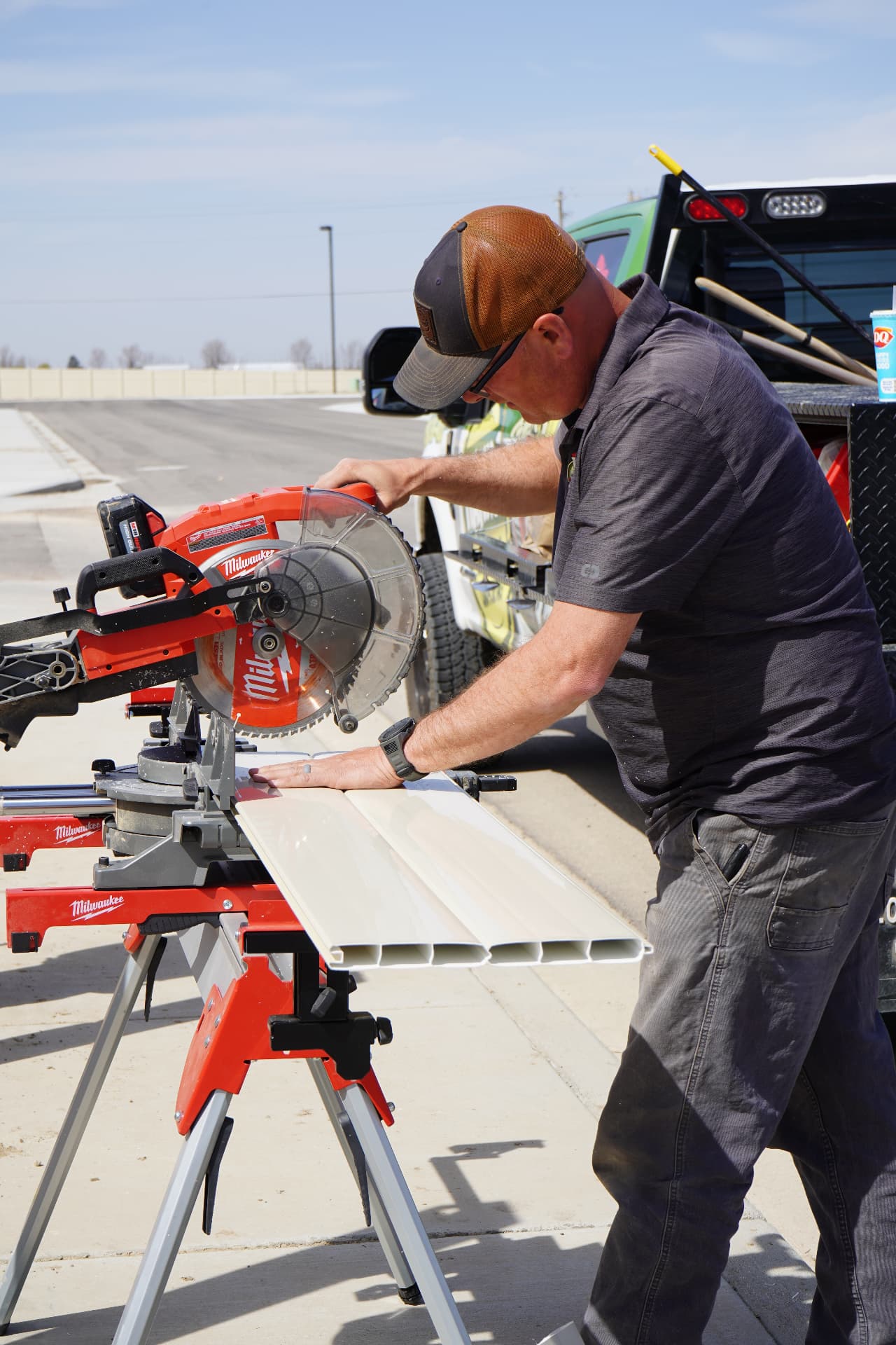 Hanks crew member cutting vinyl fence rail with a miter saw