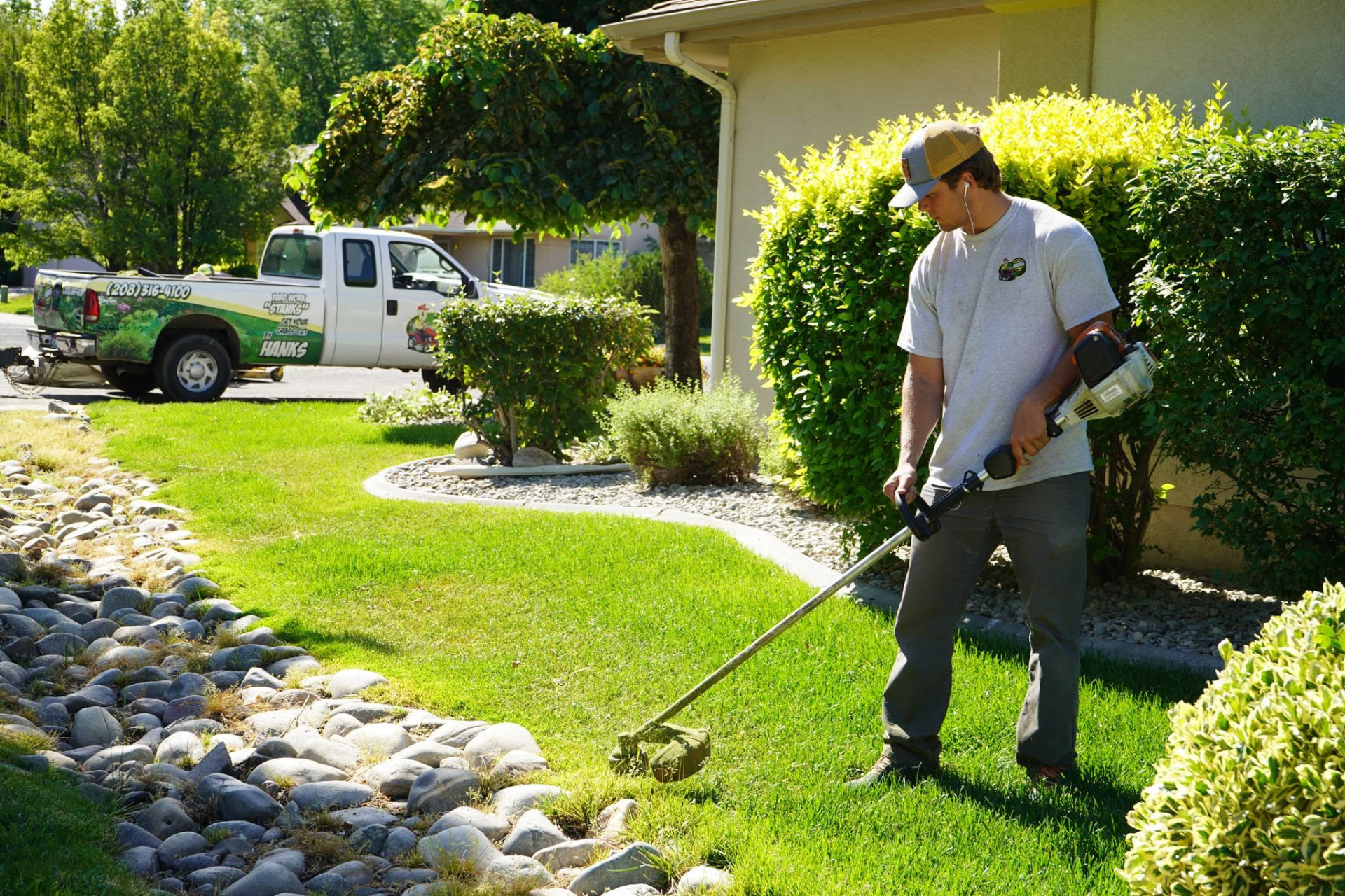 Hanks crew member trimming lawn edges with a weed whacker