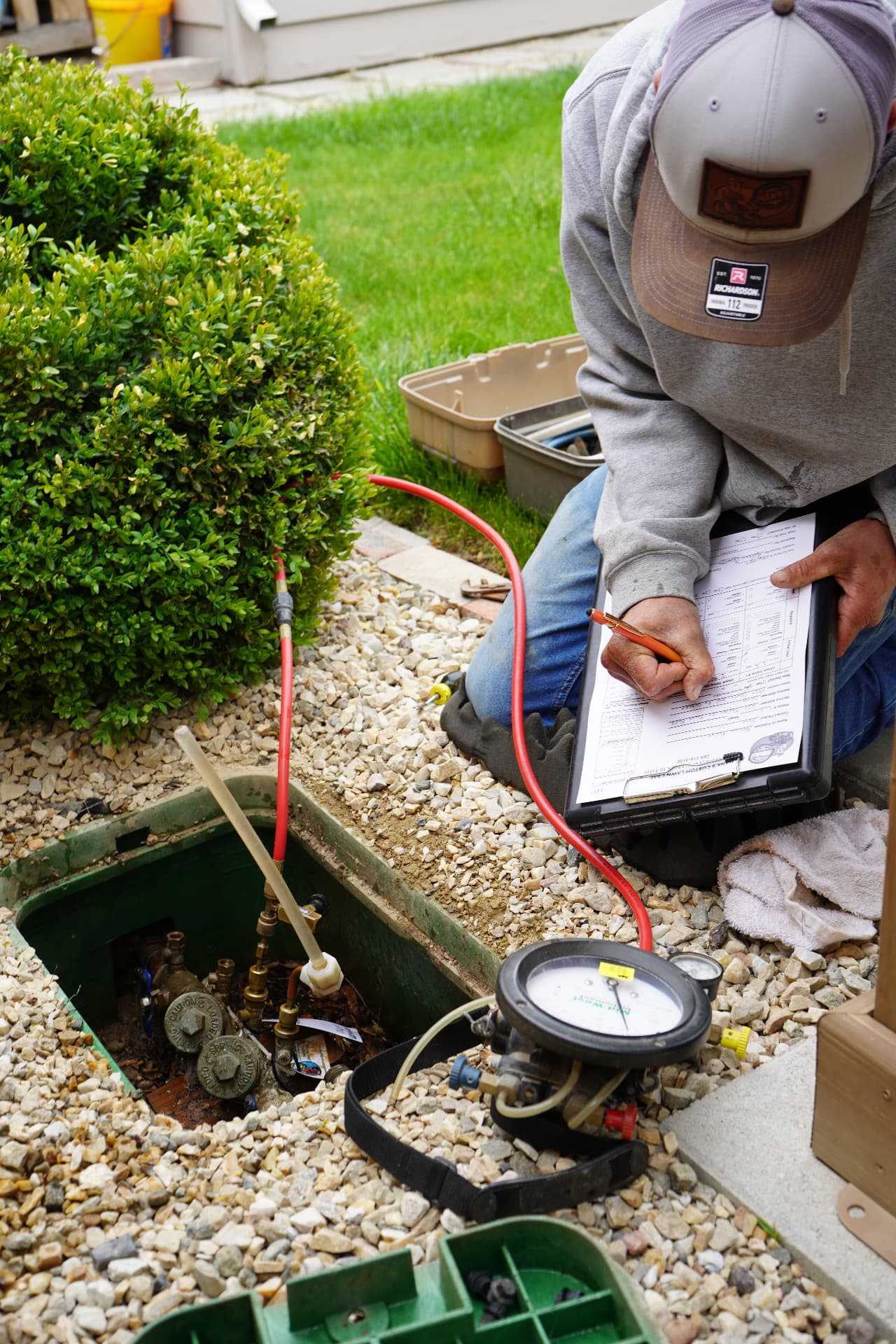 Hanks technician recording backflow test results on a clipboard