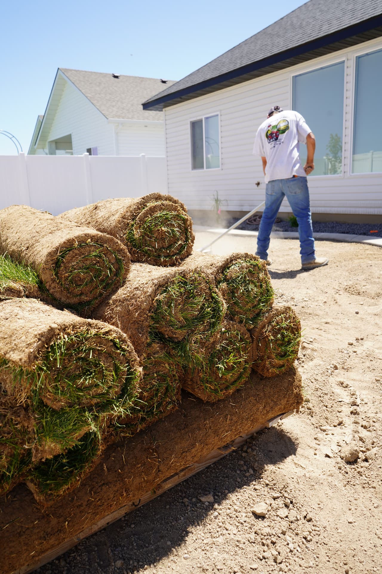 Fresh rolls of sod ready for installation with a Hanks crew member in the background