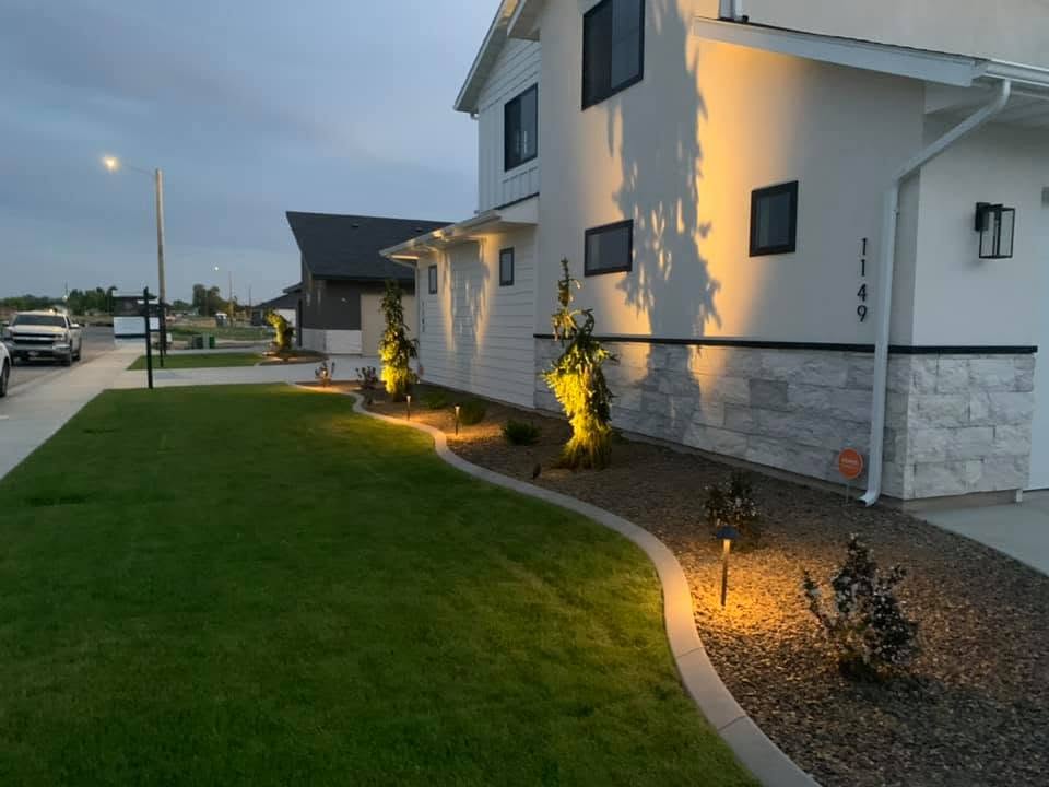 New lawn with landscape lighting and decorative curbing at dusk