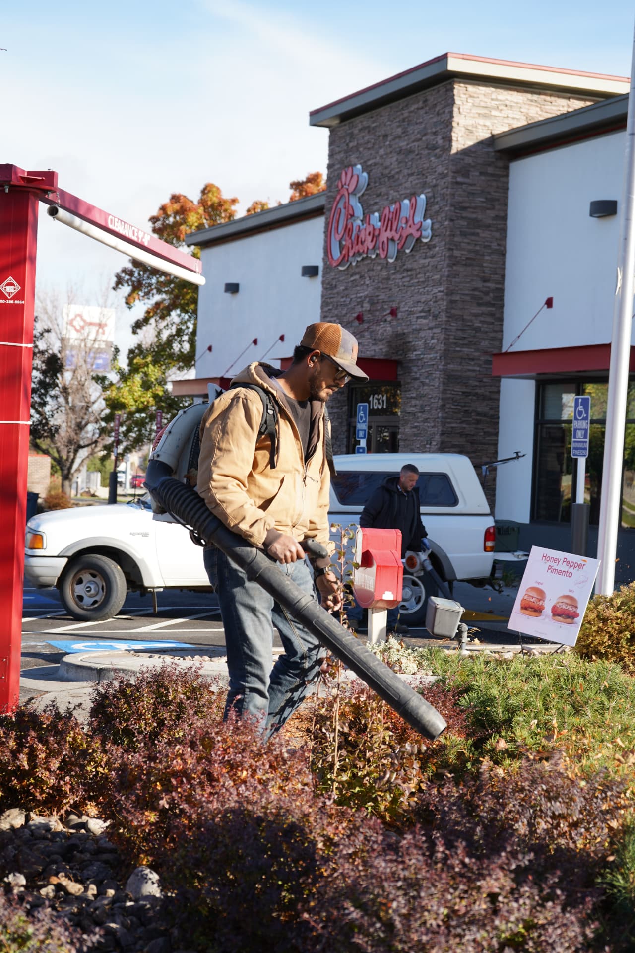 Hanks crew member clearing landscape beds with a backpack leaf blower