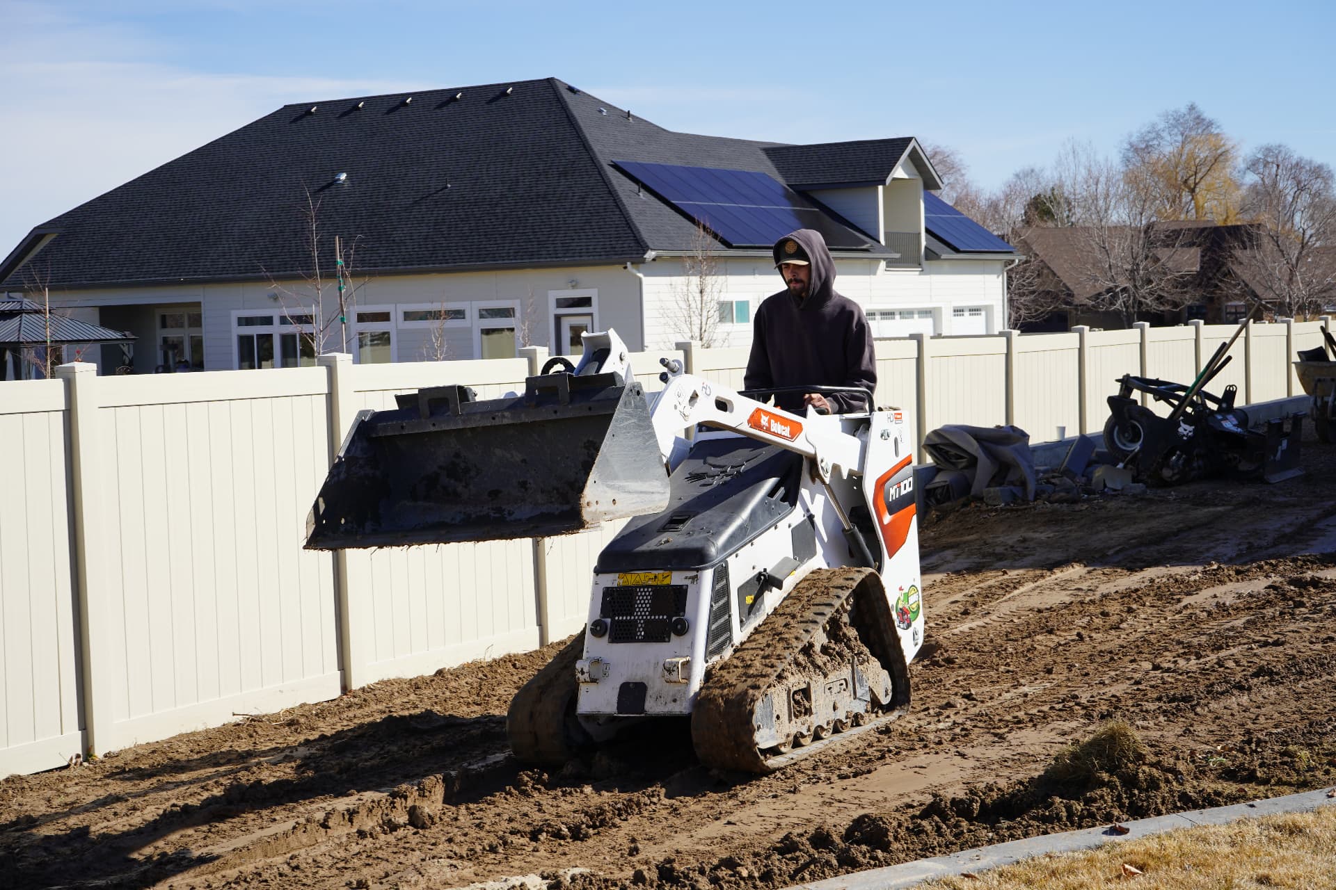 Hanks operator grading a backyard with a Bobcat MT100 mini track loader