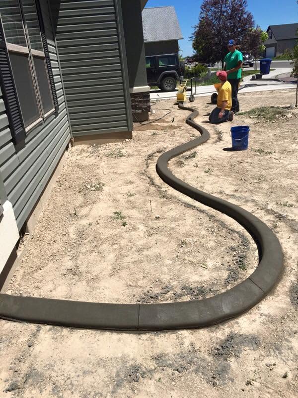 Fresh decorative concrete curbing being installed around a landscape bed