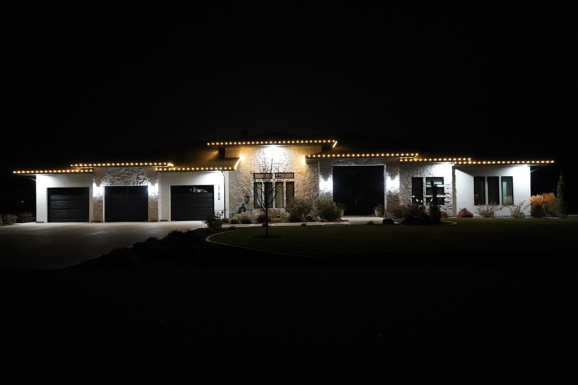 Home with warm white LED roofline lights glowing at night