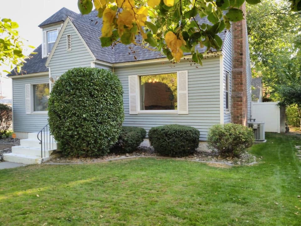 Professionally shaped shrubs in front of a light blue home