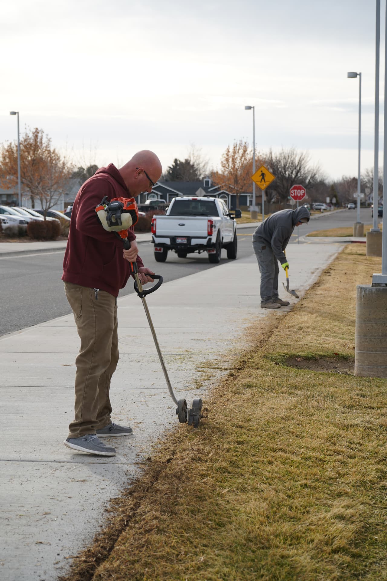 Hanks crew members edging a lawn along a residential sidewalk