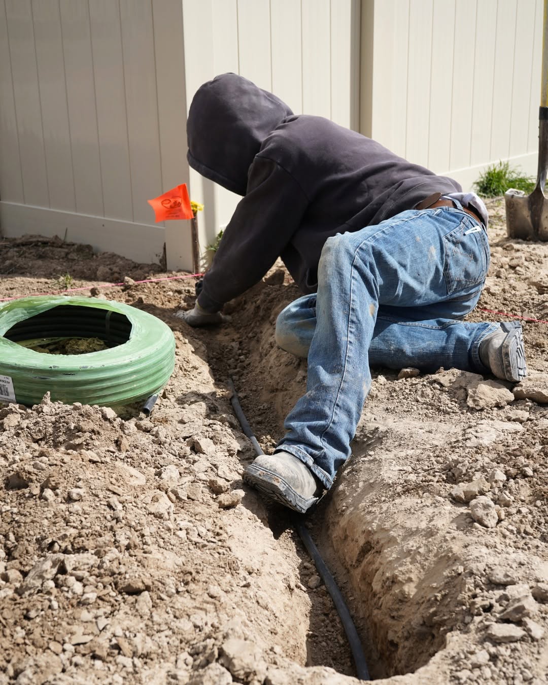 Technician installing sprinkler lines in a trench during a new system install