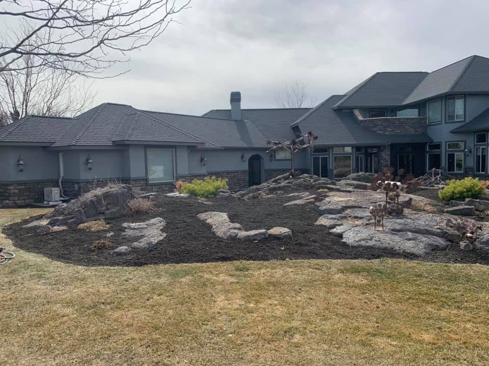 Finished rock and mulch landscape bed with boulders in front of a modern home