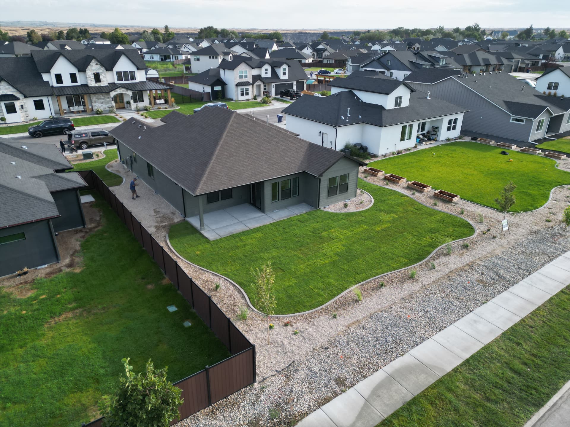 Finished backyard with fresh sod lawn, curved decorative curbing and wooden planter boxes