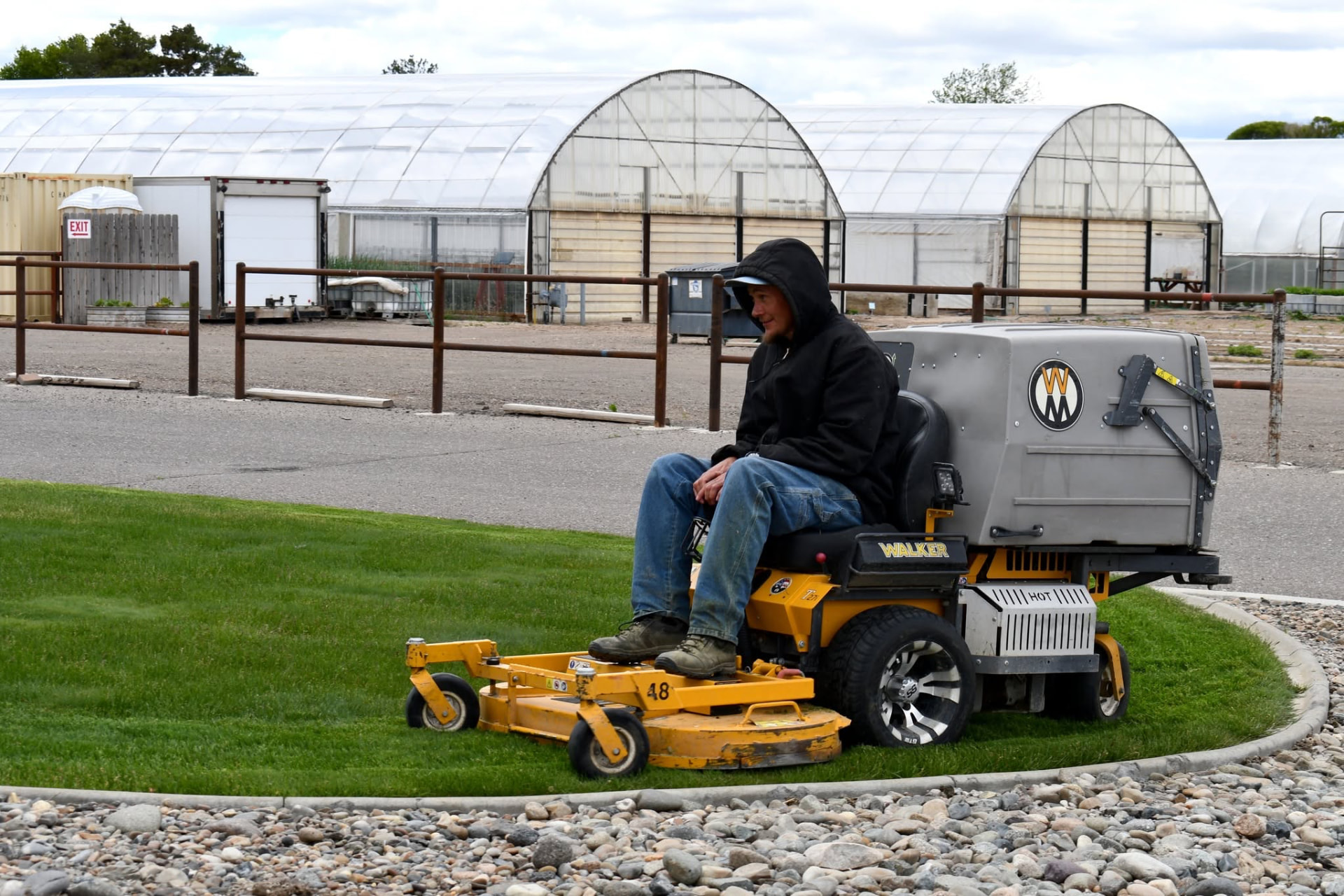 Technician on a Walker riding mower trimming a lawn