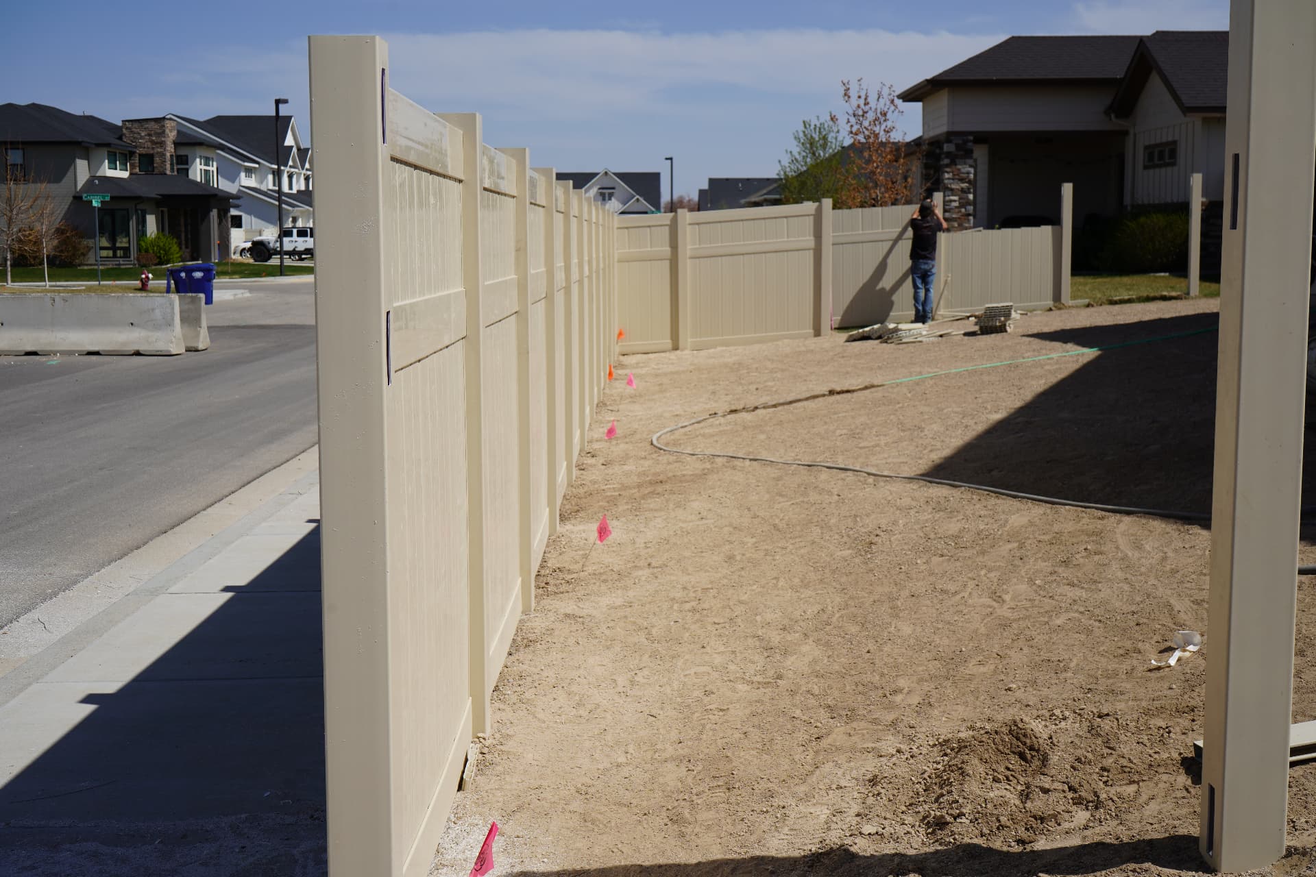 New tan vinyl privacy fence installed along a residential street