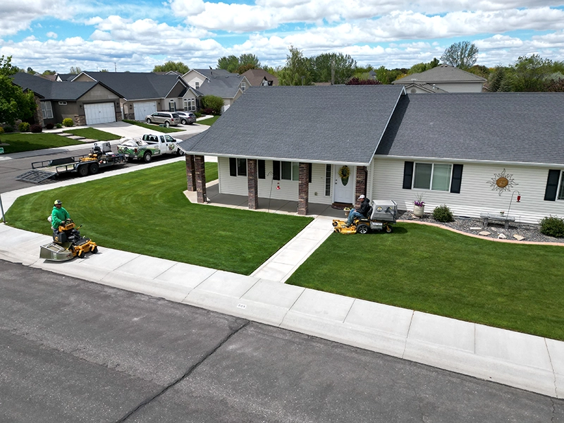 Two Hanks crew members mowing a pristine residential lawn