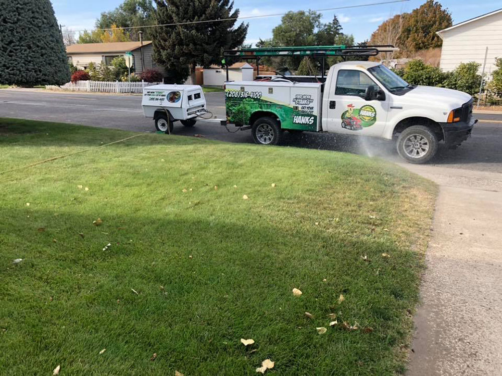 Hank's Custom Lawncare truck parked by the curb for landscaping services to test sprinkler backflow